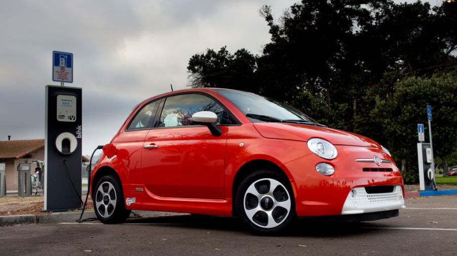 A red Fiat 500e plugged in and charging