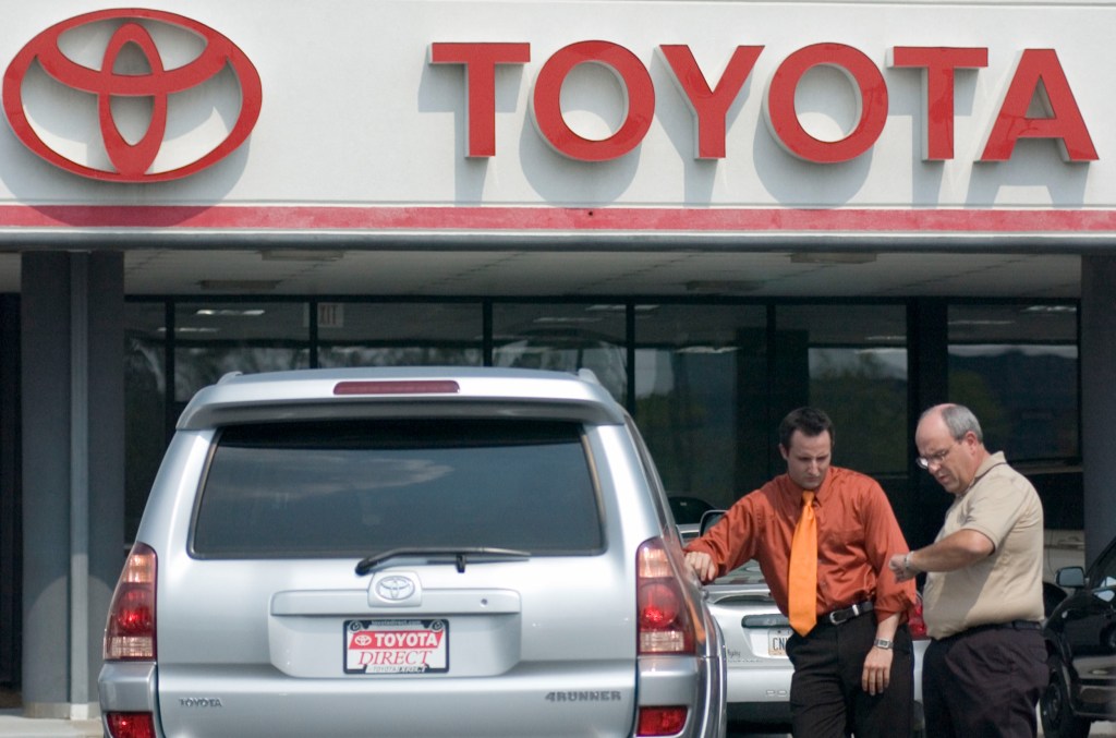 A salesman talks with a customer about a Toyota Motor 4Runner SUV. 