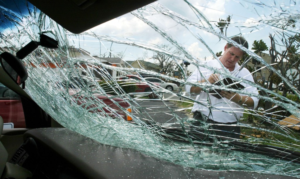 An insurance adjuster views a broken windshield.