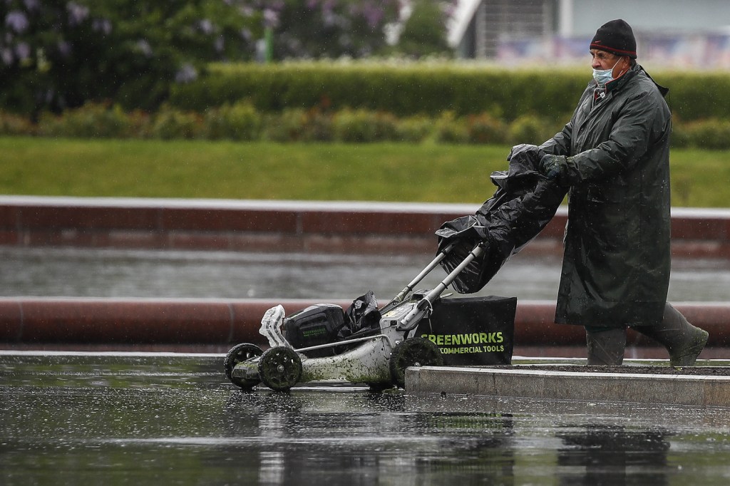 A man using a Greenworks electric push lawn mower. Greenworks makes one of the best electric push lawn mowers, according to Bob Vila