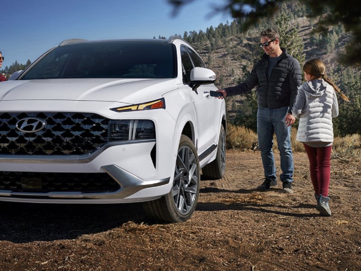 A man and his daughter are getting into a 2021 white Hyundai Santa Fe.