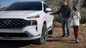 A man and his daughter are getting into a 2021 white Hyundai Santa Fe.