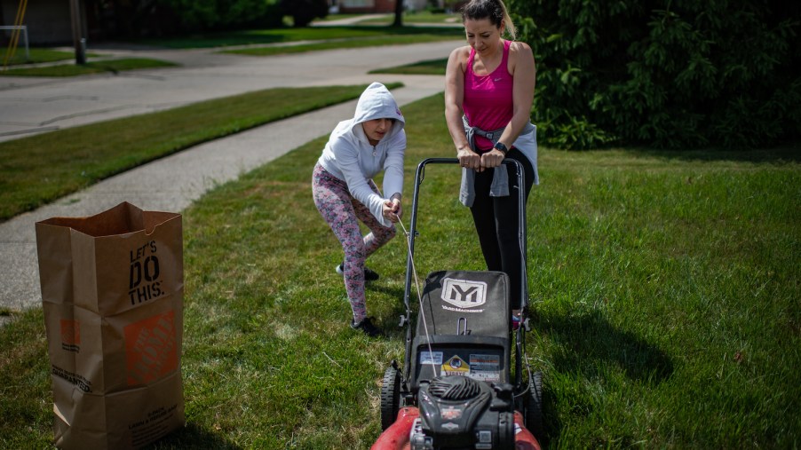 Two people trying to start a lawn mower, if your lawn mower won't start, there's likely a reason why