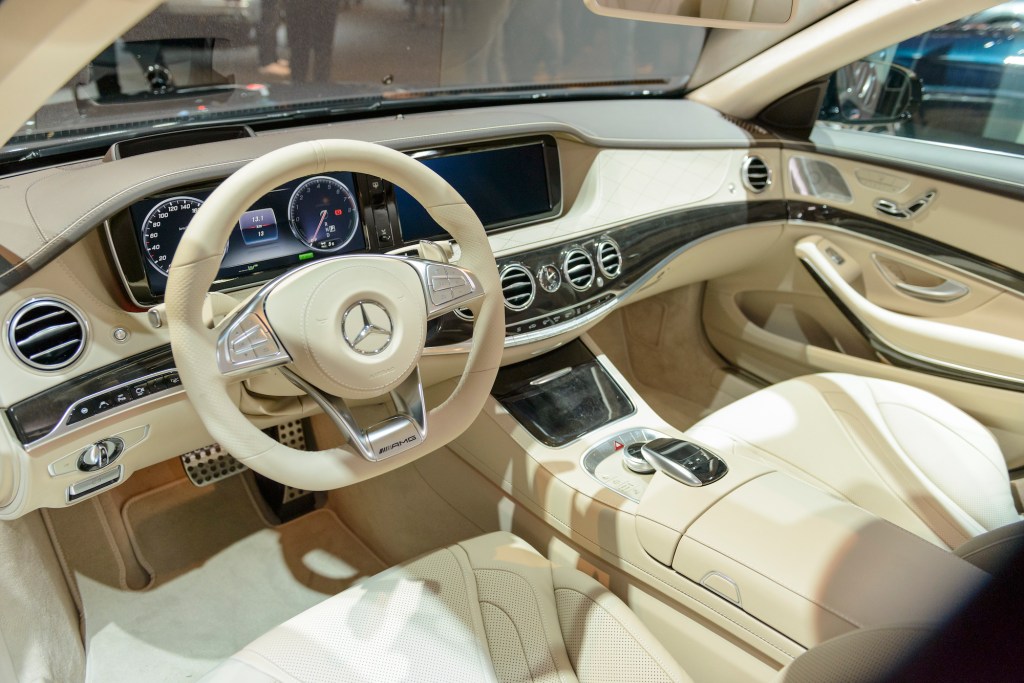  Dashboard on a Mercedes-Benz S500e Plug-in Hybrid luxury limousine sedan fitted with light leather seats, wood trim and a large information display on the dashboard. 