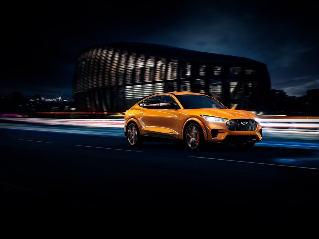 A yellow 2021 Ford Mustang Mach-E races through a city. 