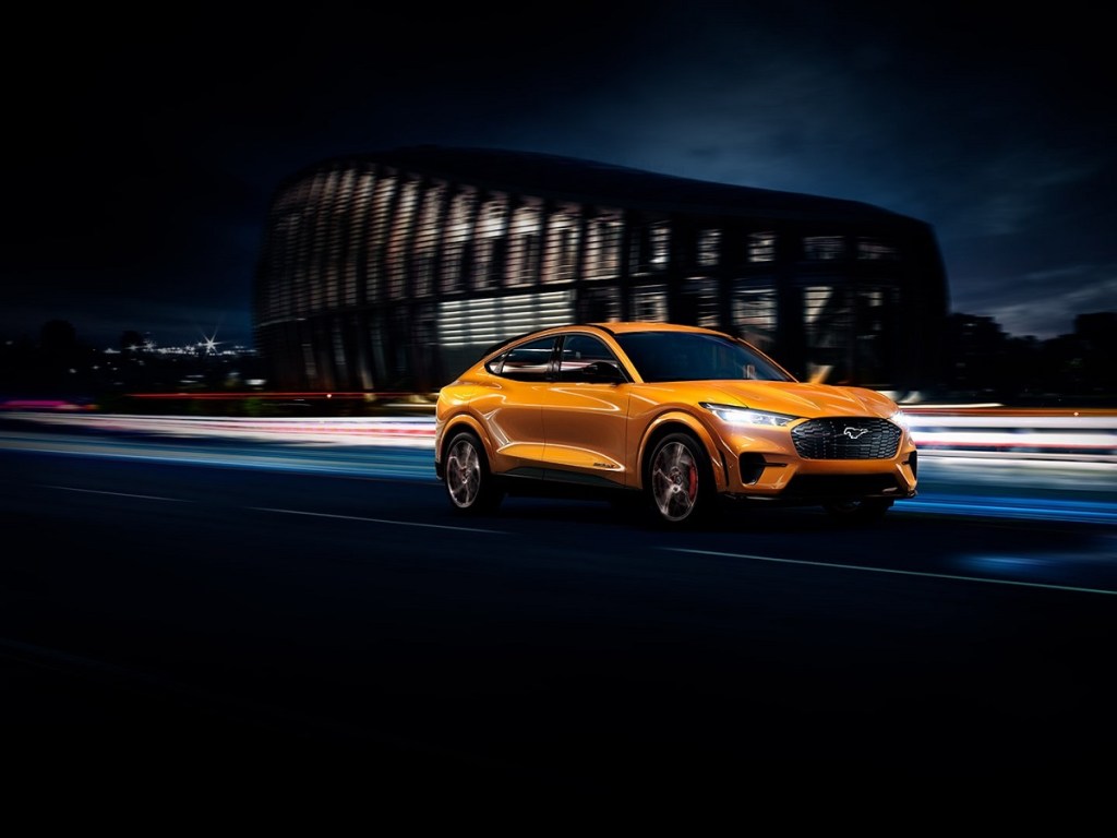 A yellow 2021 Ford Mustang Mach-E races through a city.