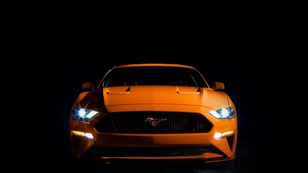 An orange 2021 Ford Mustang against a black background. 
