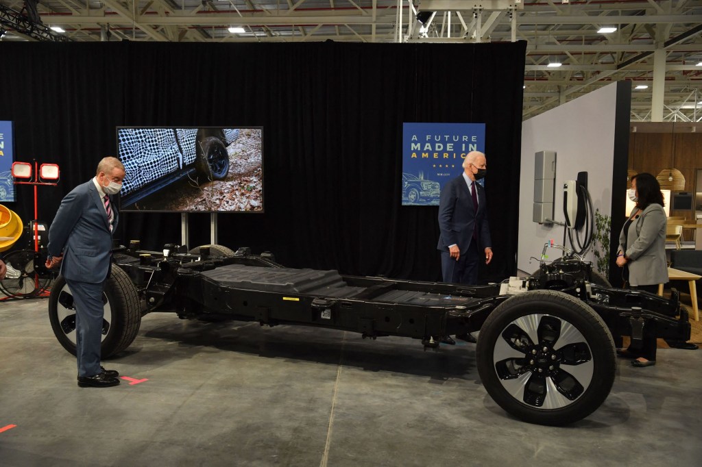 President Joe Biden examines the battery pack and chassis of a Ford EV