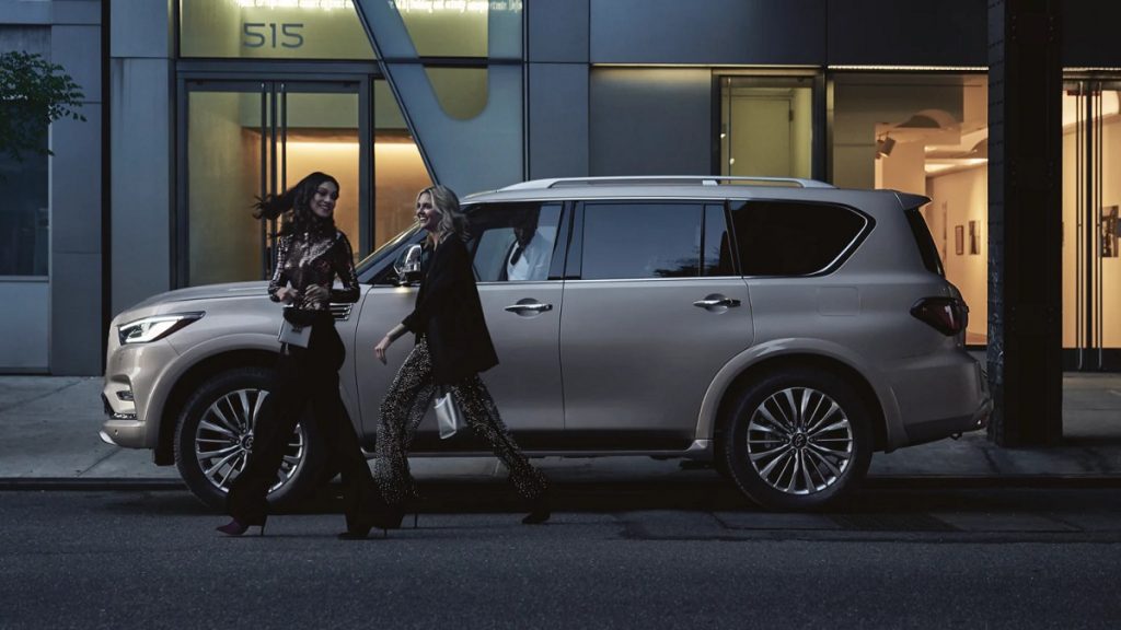 A gold 2021 Infiniti QX80 sitting outside of a store.