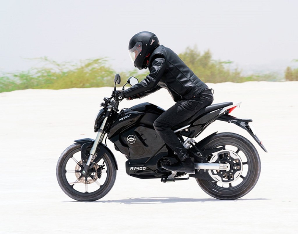 A man clad in all black on a black electric motorcycle.