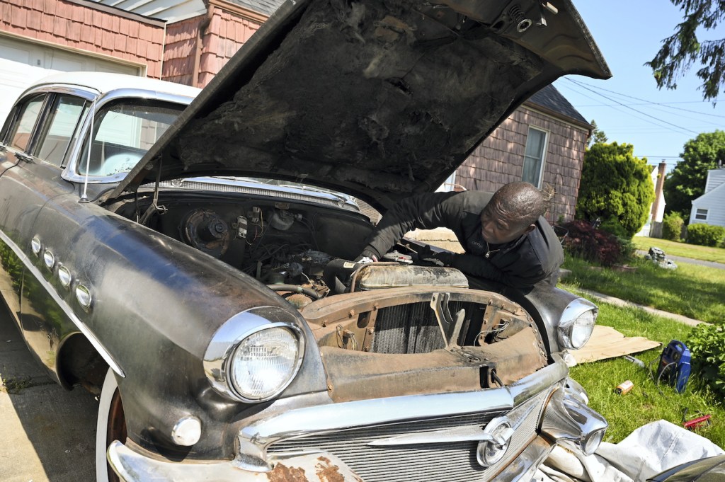 Long Island man works on engine of classic car 1956 Buick