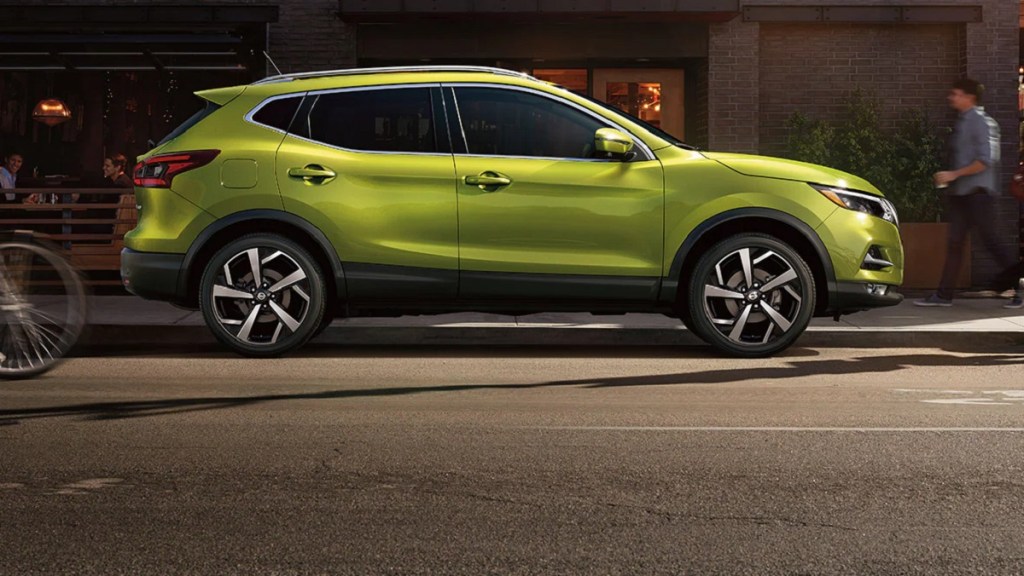 A green 2021 Nissan Rogue Sport is parked on a city curb.