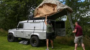 Camper Emilio Folegnani (L) is helped by fellow camper Gethyn Rees as he sets up his rooftop tent at Byecross Farm Campsite, Preston