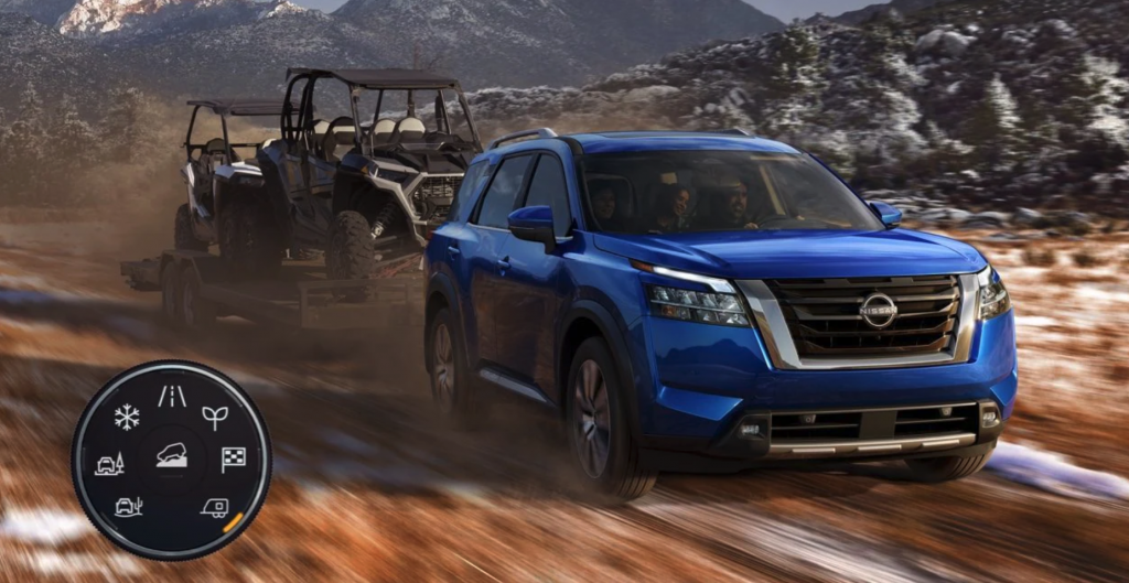A blue 2022 Nissan Pathfinder towing an ATV with drive modes shown