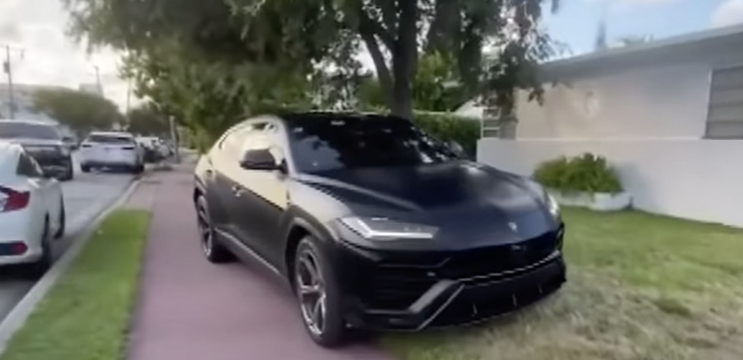 An image of a Lamborghini Urus parked on a sidewalk.
