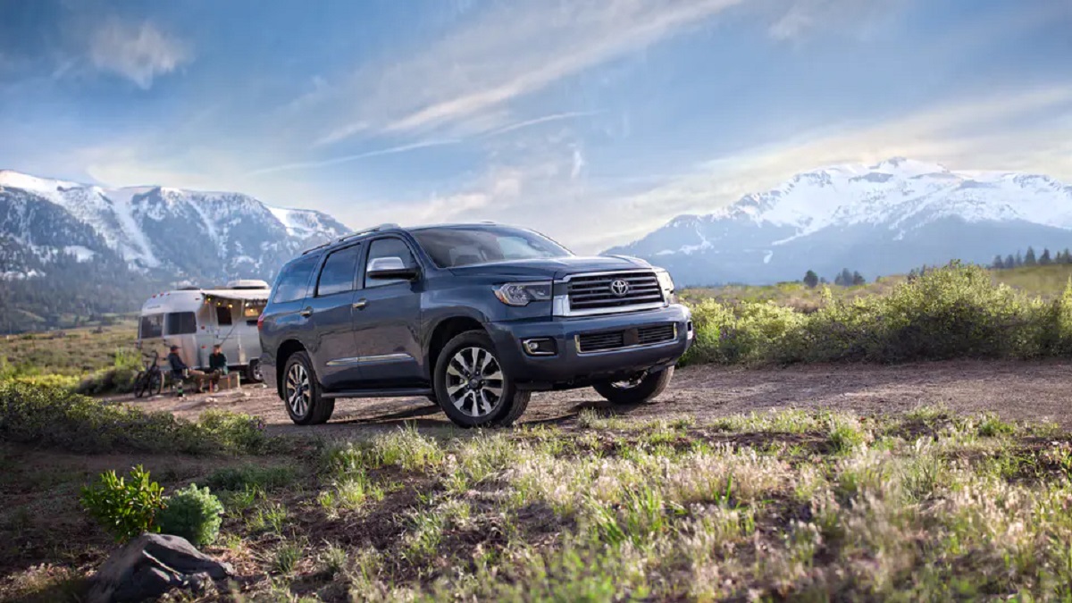 A blue 2021 Toyota Sequoia drives up a grassy mountain side.