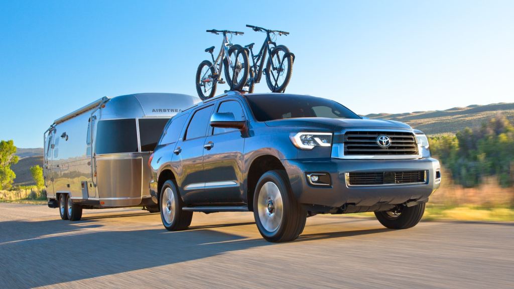 A blue 2021 Toyota Sequoia with a trailer driving up a mountain.