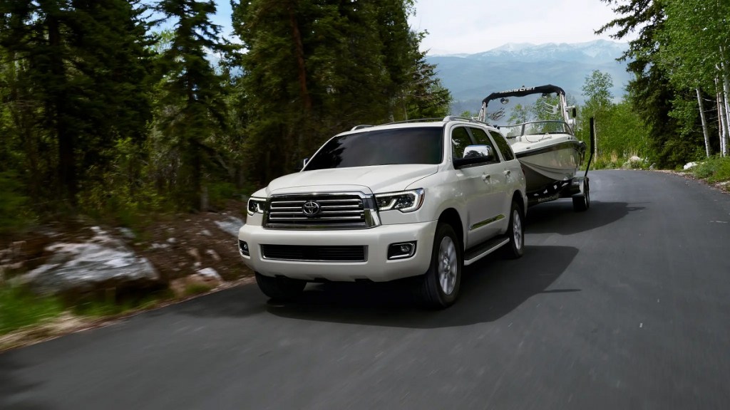 A white 2021 Toyota Sequoia tows a boat. 