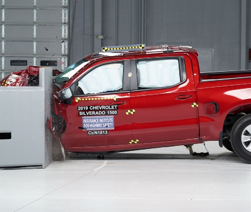 A red Chevy Silverado 1500 is smashed into a wall inside the IIHS laboratories.