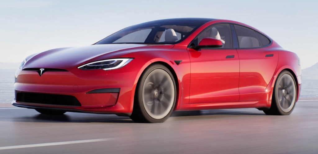 A red Tesla Model S Plaid drives down a road