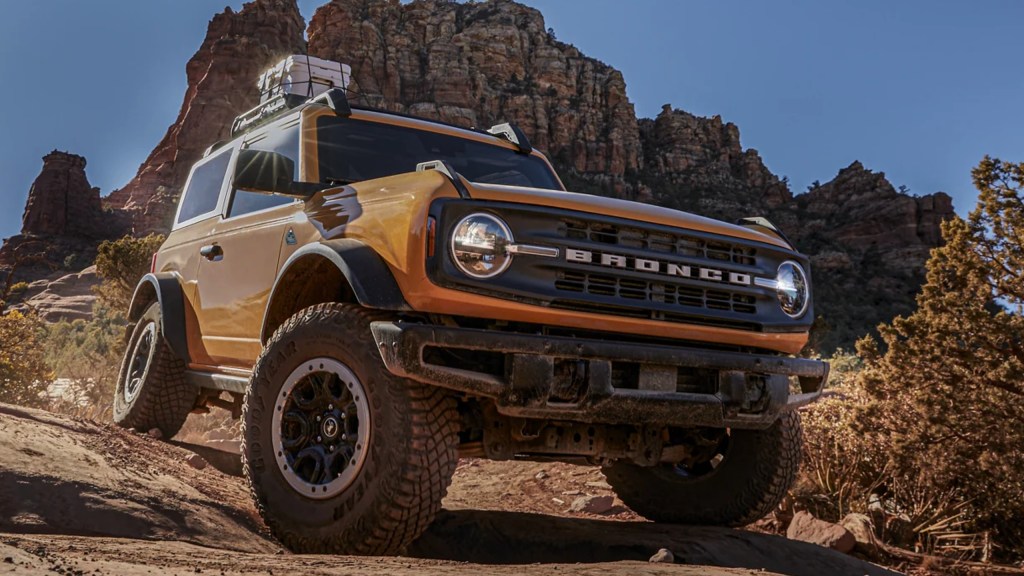 A yellow 2021 Ford Bronco SUV is driving off-road.  