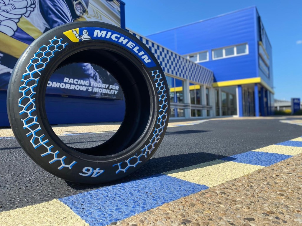 The Michelin racing tire with 46% sustainable materials unveiled at the 2021 Movin'On Summit on a racetrack by a blue-and-yellow Michelin building