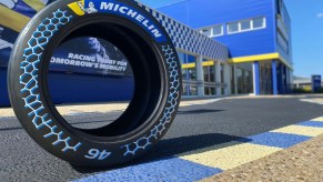The Michelin racing tire with 46% sustainable materials unveiled at the 2021 Movin'On Summit on a racetrack by a blue-and-yellow Michelin building