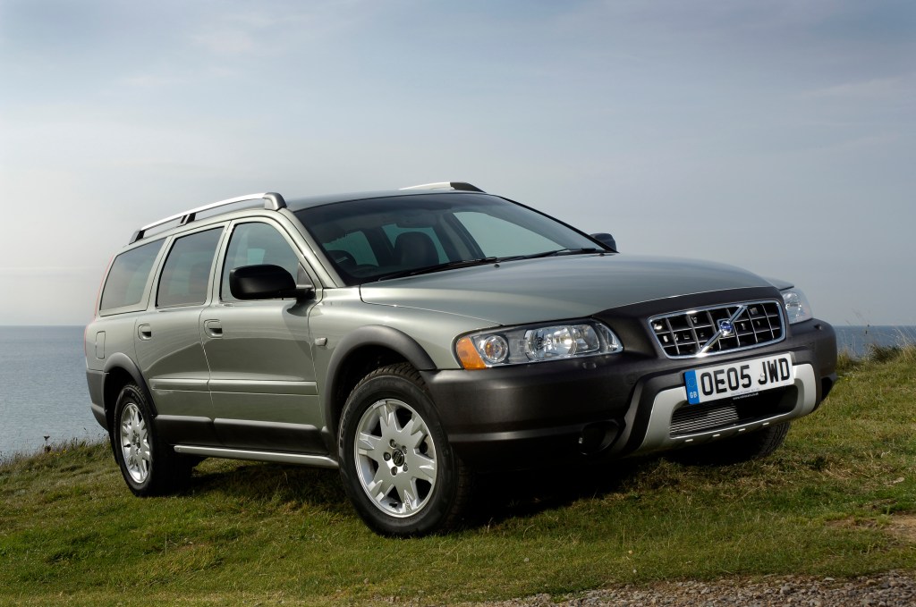 A silver Volvo XC70 SUV parked on a hill overlooking water