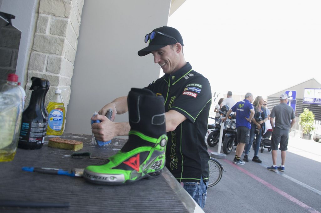 Yamaha Moto3 rider Pol Espargaro cleans his green-and-black racing motorcycle boots at the track