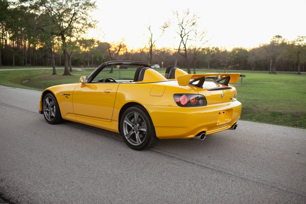 A yellow open-roof Honda S2000 
