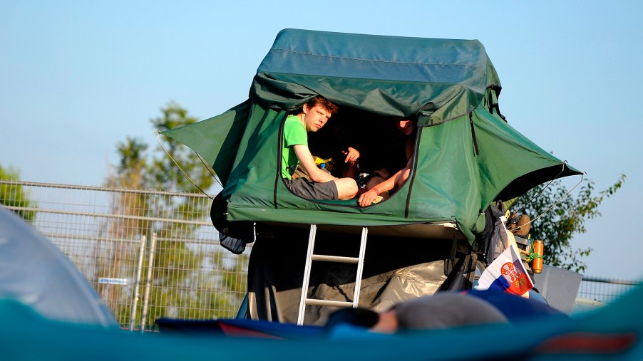 Two people in a tent placed on a car's roof