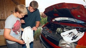Two men check a car's transmission fluid