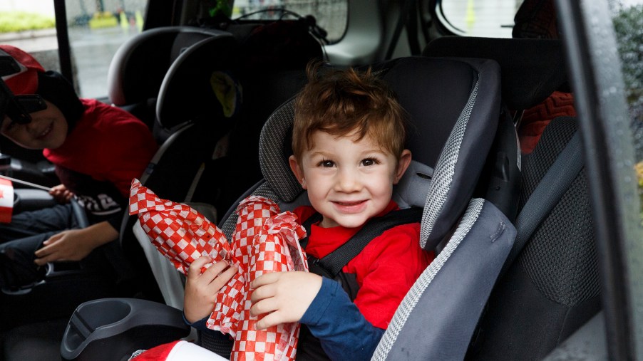 Two children in car sats in the back of a vehicle