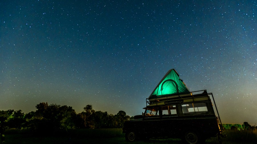 A Land Rover with a roof tent parked at a dark-sky RV campground at night