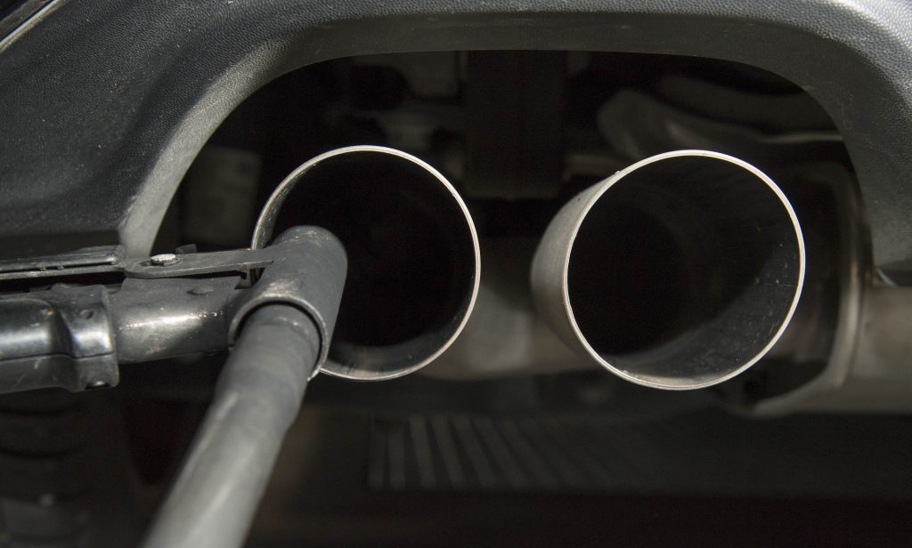 A hose sits near the exhaust of a diesel vehicle to perform an emissions test