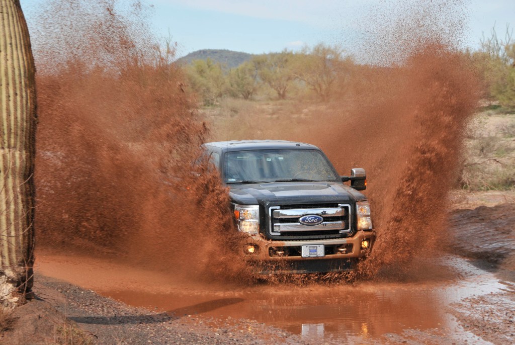 A diesel pickup truck splashes through a mud puddle