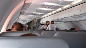 Flight attendants wearing facemasks serve passengers during a flight in October 2020