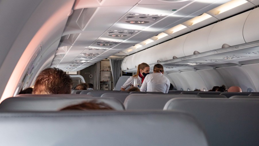 Flight attendants wearing facemasks serve passengers during a flight in October 2020