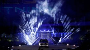 A silver Ford F-150 electric pickup truck on display in front of theatrical lighting