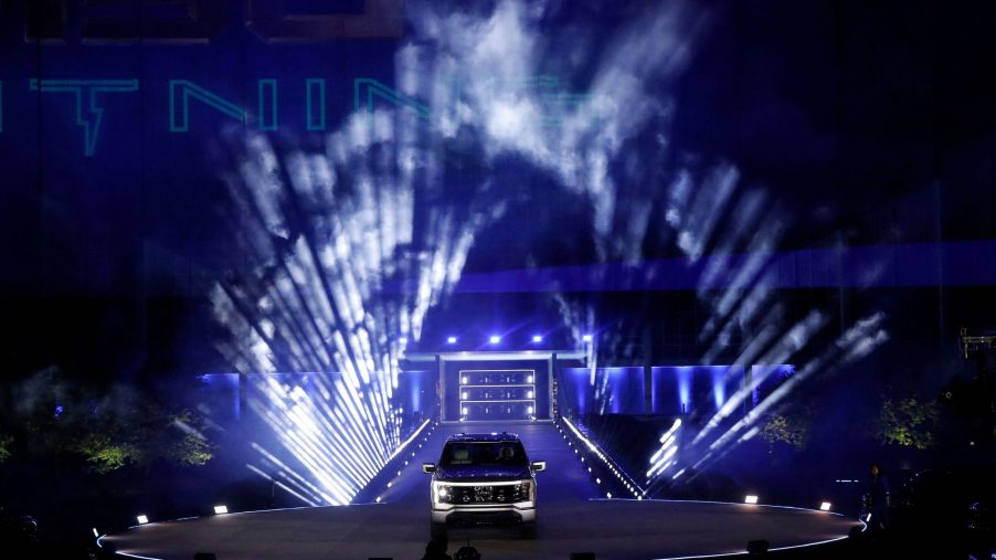 A silver Ford F-150 electric pickup truck on display in front of theatrical lighting