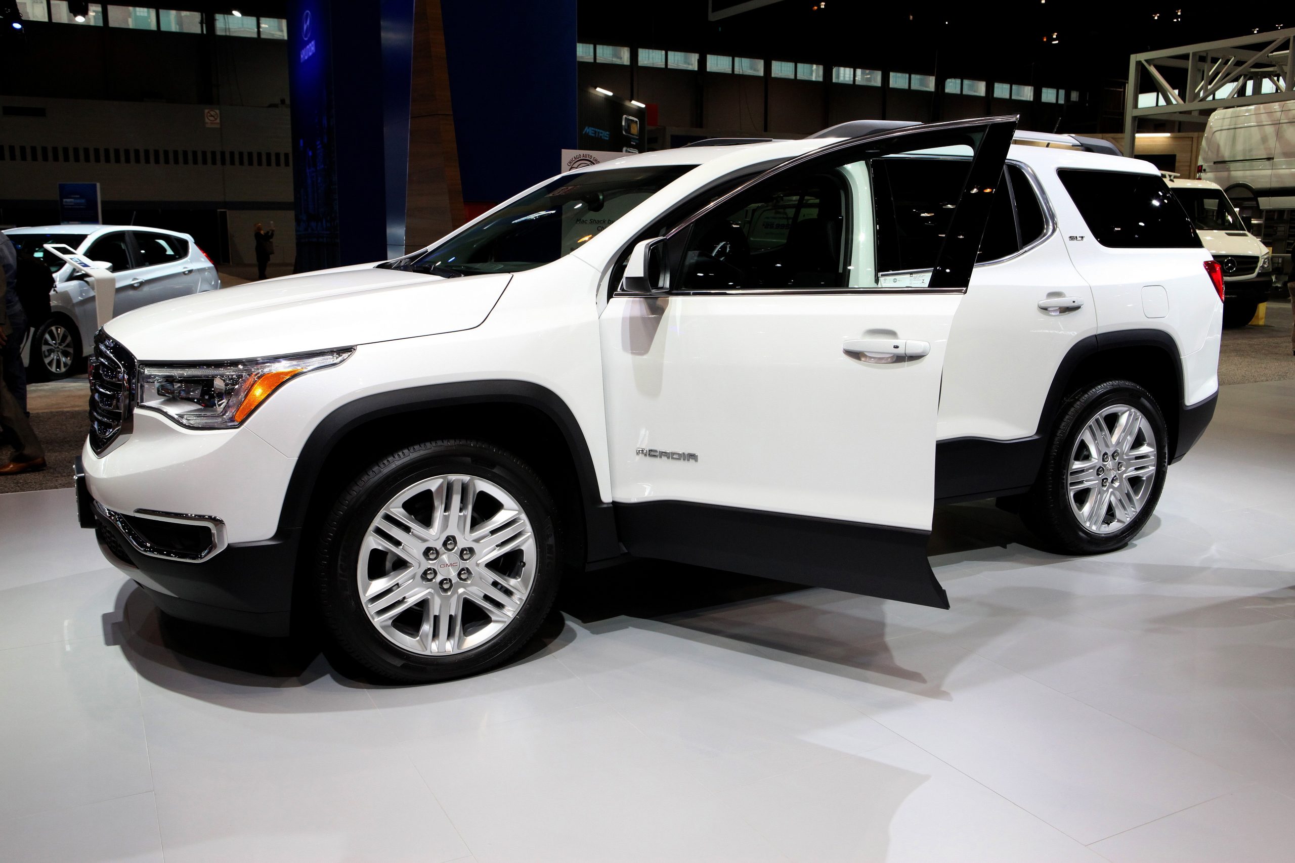 A white gmc acadia with an open drivers door
