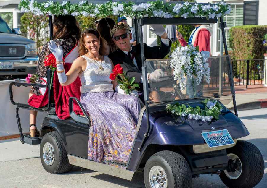 Barbara and Michael Lawler wave to residents from their golf cart during the Balboa Island Golf Cart Parade in Newport Beach on Sunday, June 6, 2021