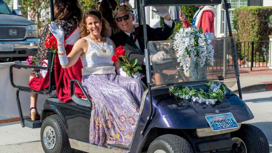 Barbara and Michael Lawler wave to residents from their golf cart during the Balboa Island Golf Cart Parade in Newport Beach on Sunday, June 6, 2021