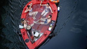 Four people sit inside a red hot tub boat