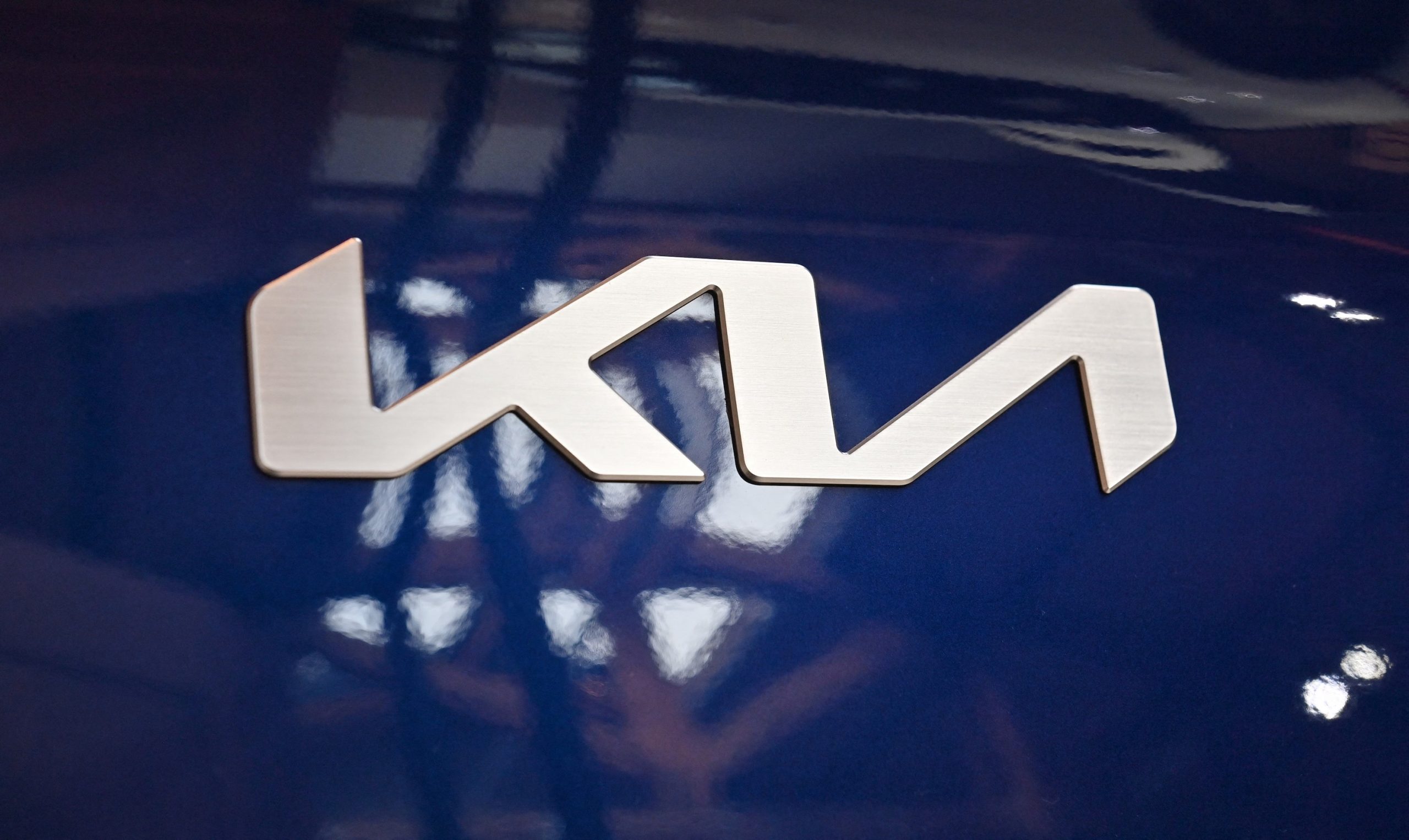 A silver Kia logo emblem on a blue EV6