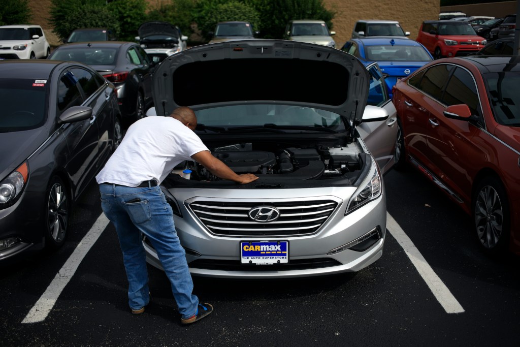 A customer inspects a pre-owned Hyundai while shopping for a used vehicle at a CarMax dealership.