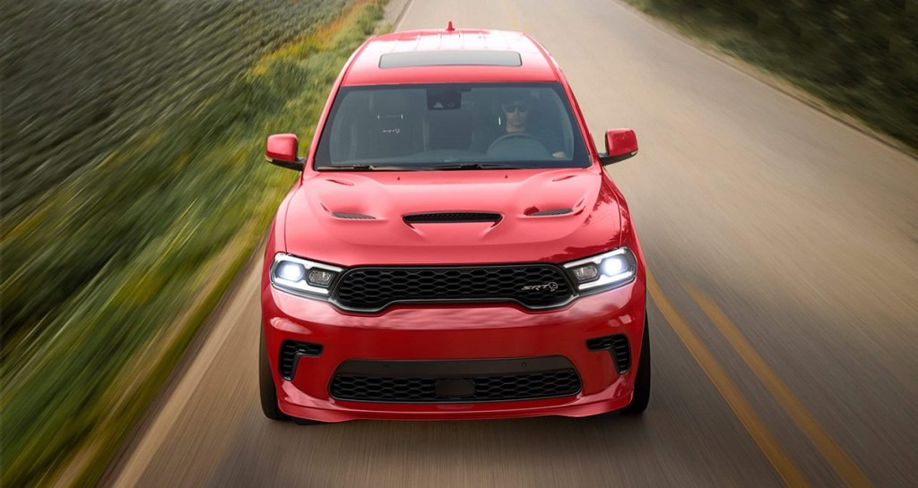 A red 2021 Dodge Durango drives down a road with grass on the side.