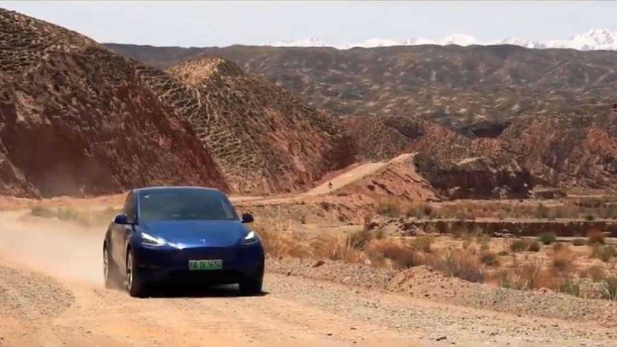 A dark blue Tesla drives through the mountains of China.