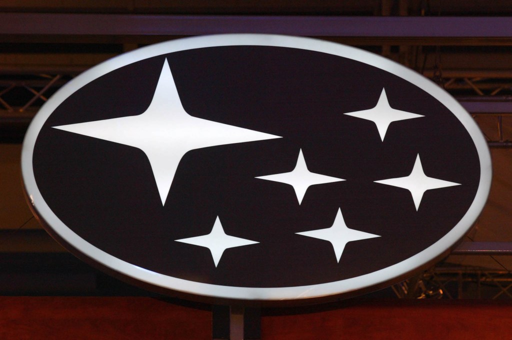 A white Subaru oval logo with 6 stars on a dark background