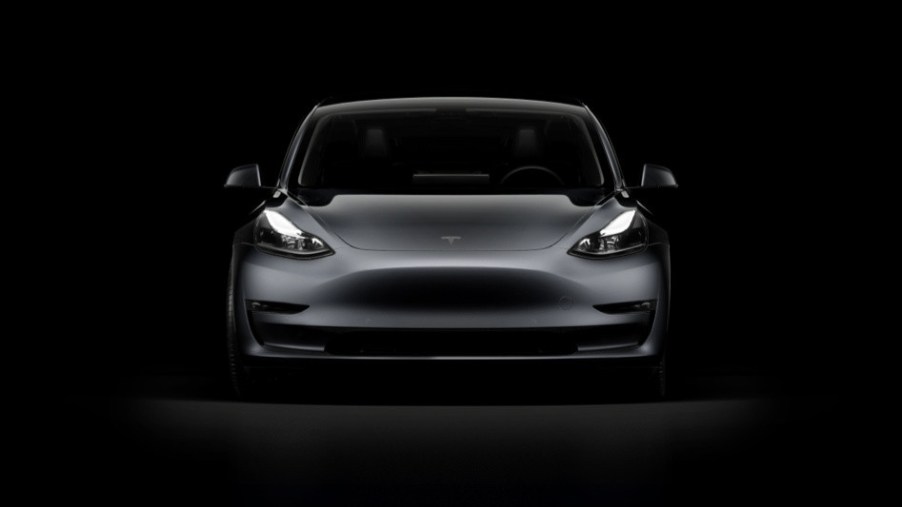 A dark gray Tesla Model 3 against a black background. The Tesla Model 3 police car is ready to be trialed in the U.K.